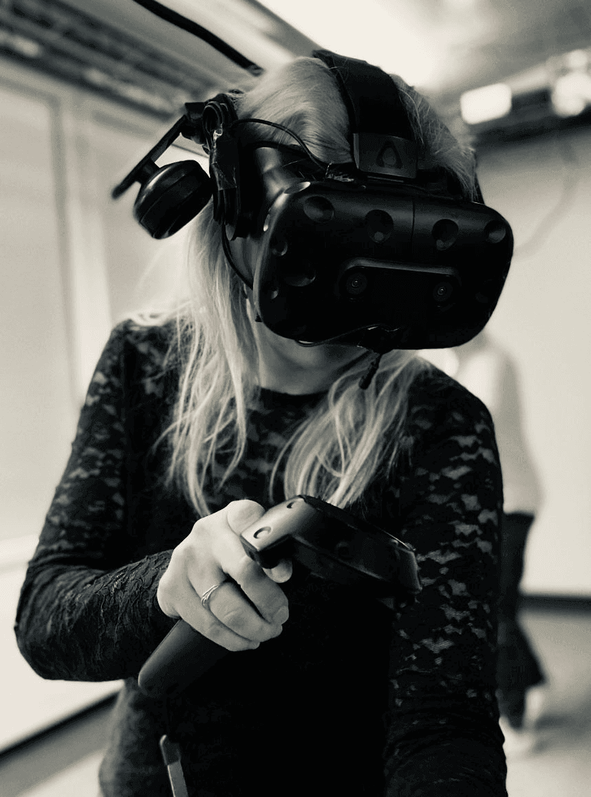Eine Person, die ein Virtual-Reality-Headset trägt und einen Controller in der Hand hält, taucht in ein VR-Erlebnis ein.